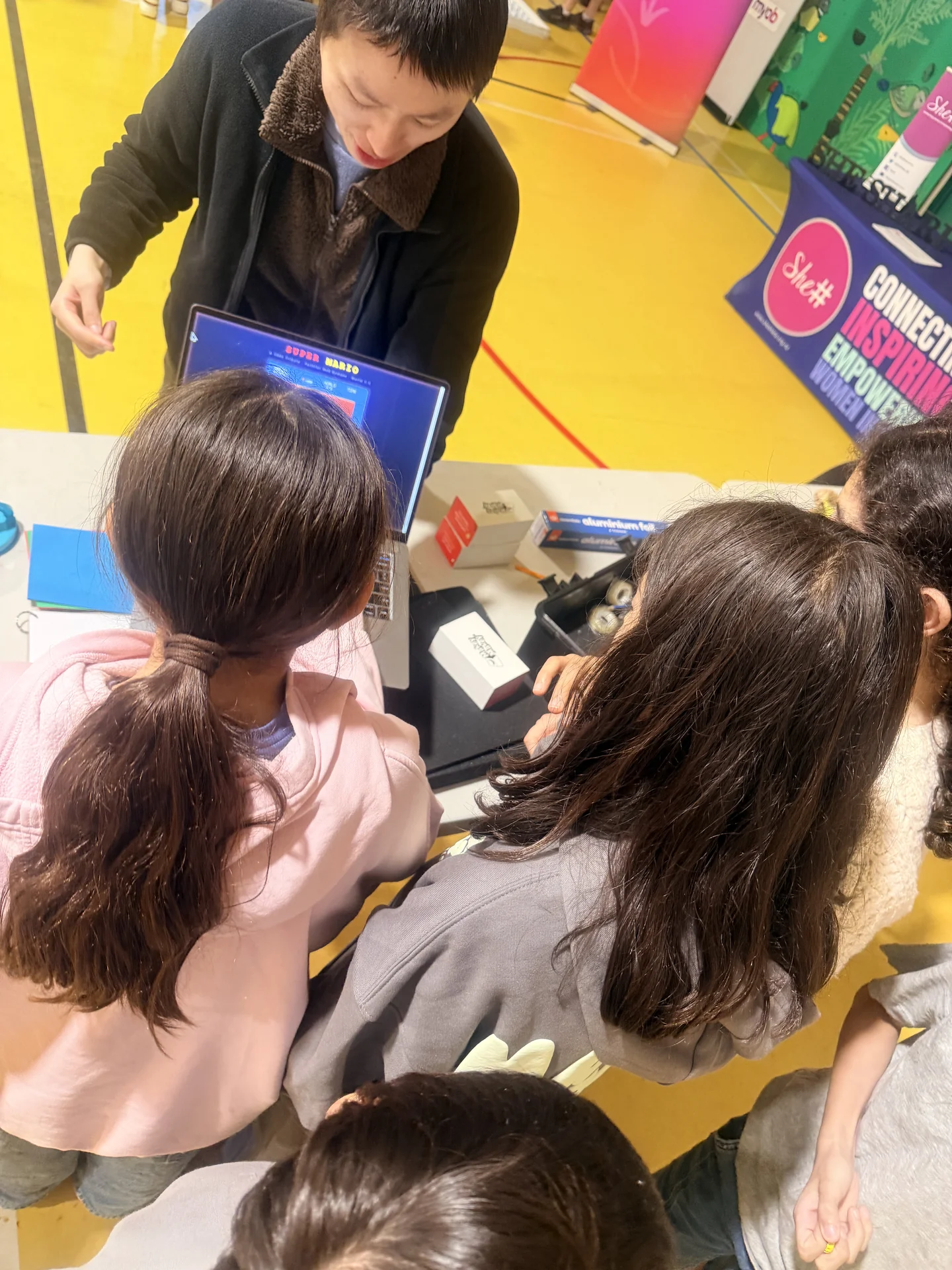 Young participants take part in a hands-on electronics activity with a laptop and Makey Makey materials