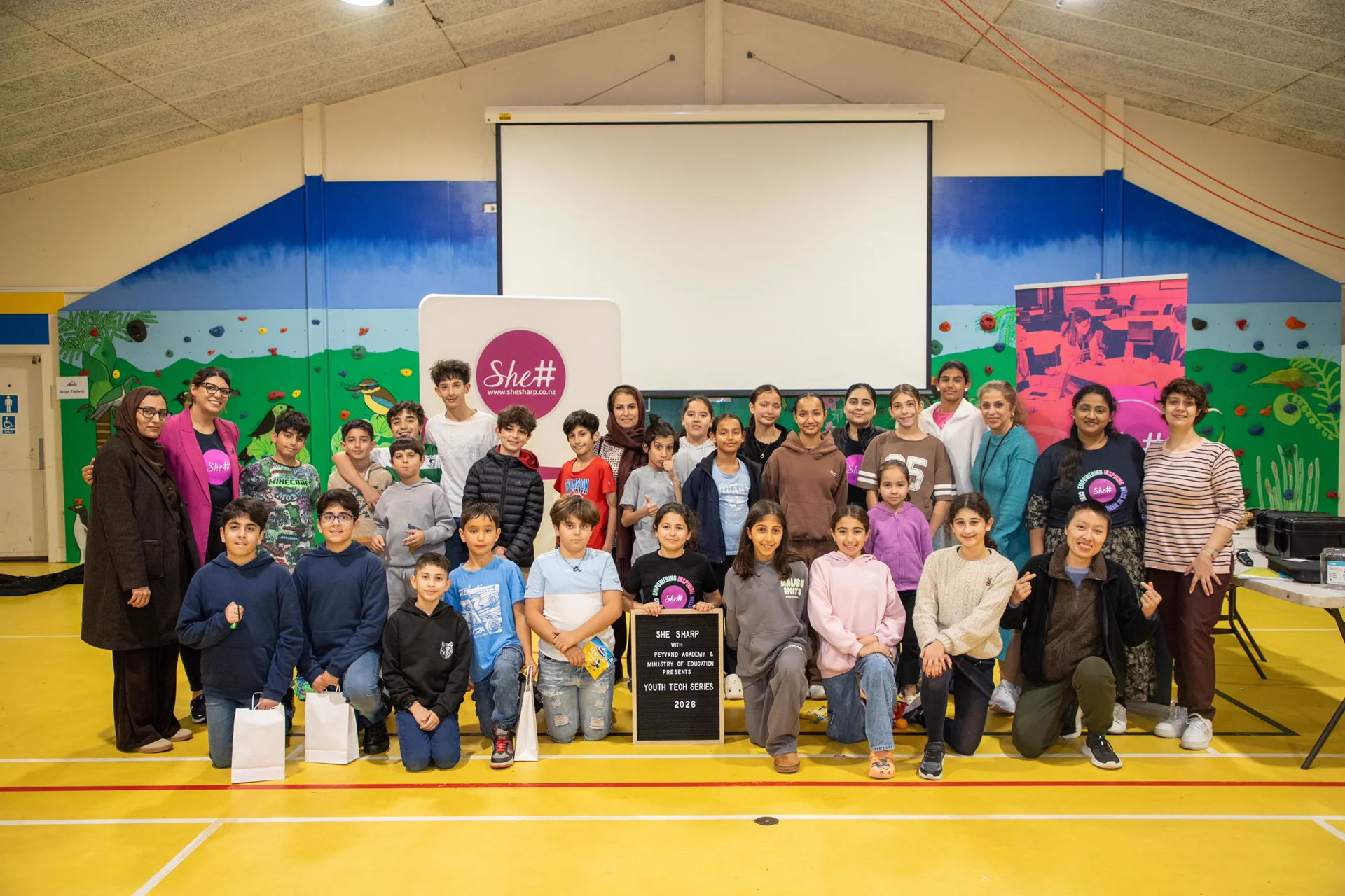 Workshop participants and facilitators gather for a group photo in front of the SheSharp Youth Tech Series 2026 sign